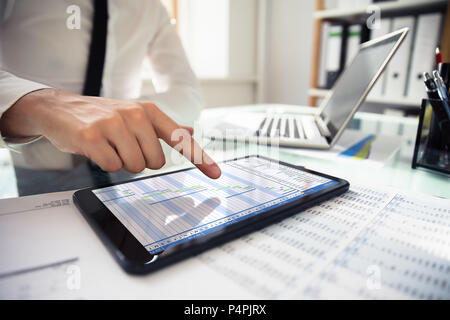 Close-up Of A Businessperson's Hand Analyzing Gantt Chat On Digital Tablet At Workplace Stock Photo