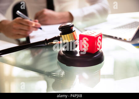 Red Cubic Block With Paragraph Symbol And Gavel On Reflective Desk Stock Photo