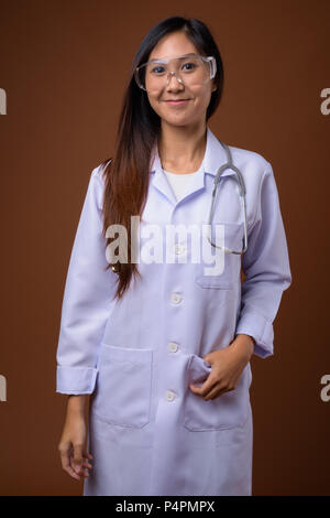 Young beautiful Asian woman doctor wearing protective glasses ag
