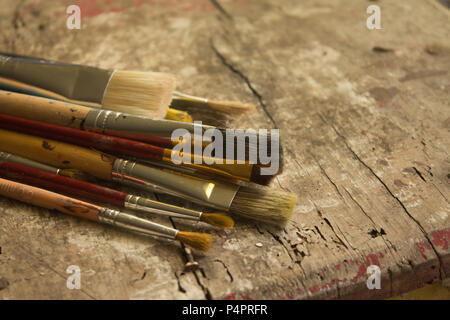 different size artist paint brushes on a rustic wood table, workshop Stock Photo