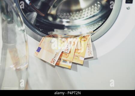 Money put to dry on the edge of the washing machine with the door opened, close up. Money laundering symbol Stock Photo