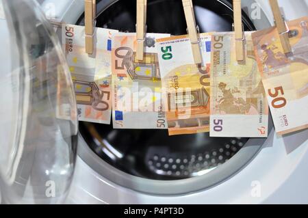 Money put to dry with hooks in front of the washing machine. Money laundering symbol, close up Stock Photo