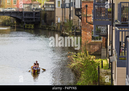 Three people in a canoe, enjoying a peaceful, warm spring evening on the river Wensum in Norwich UK. Stock Photo