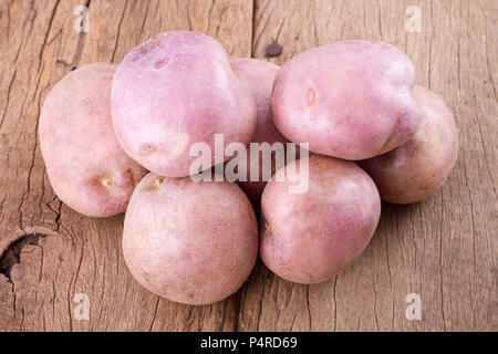 stack of potatoes on wooden table (Solanum tuberosum) Stock Photo