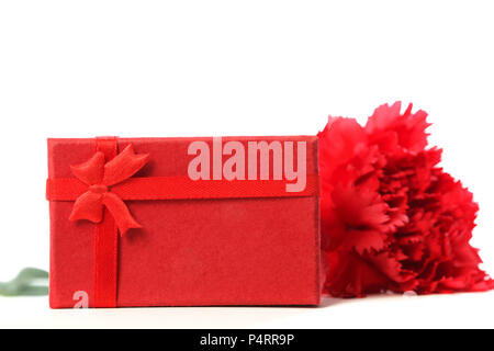 Red carnation with red gift box, isolated on a white background, studio shoot. Present with flower. Love symbol. Stock Photo