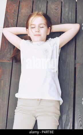 Child, girl 7-9 years old, blond hair, stand lying on a bench and sleeping, top view, retro style Stock Photo