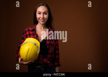 Young beautiful woman construction worker against brown backgrou Stock Photo