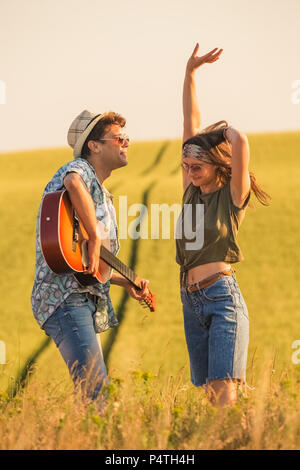 Romantic hipster couple singing their favorite song in nature. Love and summertime concept. Stock Photo