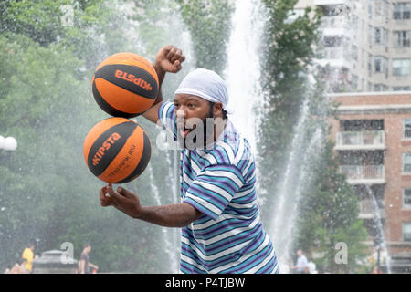 Basketball Man, a New York City street performer, balances 2 spinning basketballs on one finger. In Washington Square Park. Stock Photo