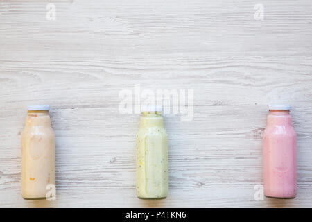 Fruit smoothies of different colors in glass jars on white wooden background. Top view, from above. Copy space. Stock Photo