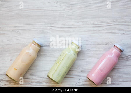 Fruit smoothies of different colors in glass jars on white wooden background. Top view, from above. Copy space. Stock Photo