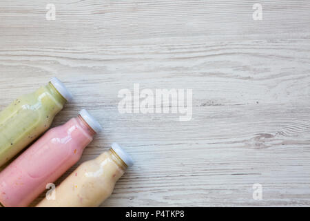 Top view, fruit smoothies of different tastes in glass jars on white wooden background. From above. Copy space. Stock Photo