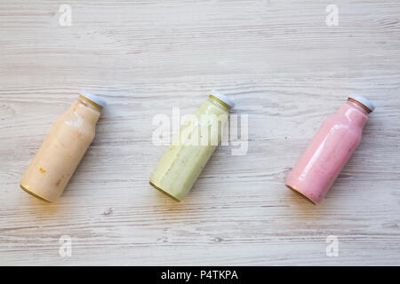 Top view, fruit smoothies of different tastes in glass jars on white wooden background. From above. Flat lay. Stock Photo