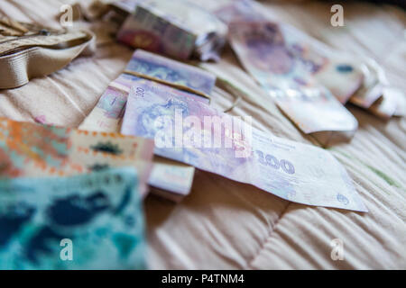 Foreign money, Argentinian pesos, spreaded out on a hotel room bed Stock Photo