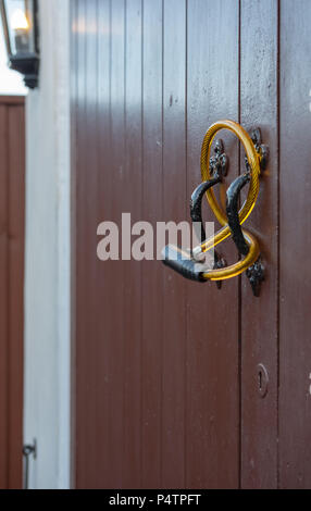 Shallow focus of a generic steel-wire bicycle antitheft device seen looped through the handles of a double door garage. Stock Photo