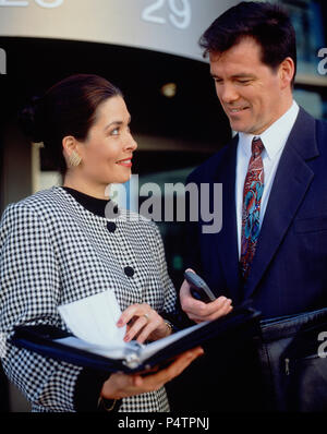 Young man and woman executive colleagues standing outside city building. Stock Photo