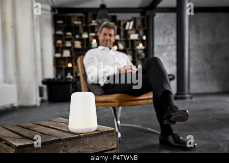 Mature man using voice-controlled digital assistant in loft Stock Photo