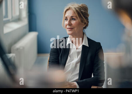 Senior businesswoman sitting on chair looking sideways Stock Photo