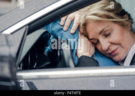 Senior businesswoman sleeping in car Stock Photo