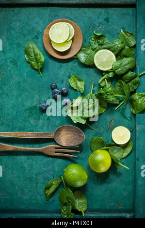 Salad ingredients and salad cutlery on green ground Stock Photo