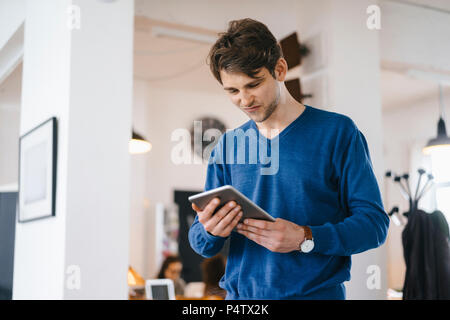 Man standing in a cafe looking at tablet Stock Photo