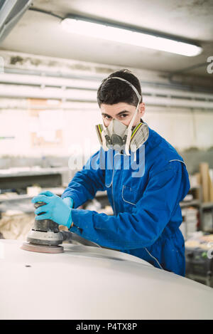 Portrait of man polishing the hood of a car in a workshop Stock Photo