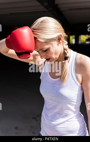 Woman with boxing gloves looking tired Stock Photo
