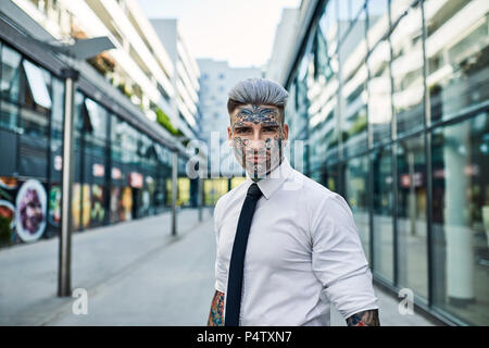 Young businessman with tattooed face walking in the city, portrait Stock Photo