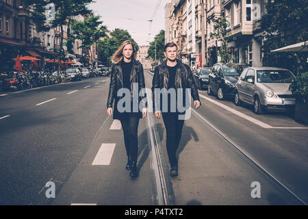 Young couple wearing black matching clothes walking side by side on the street Stock Photo
