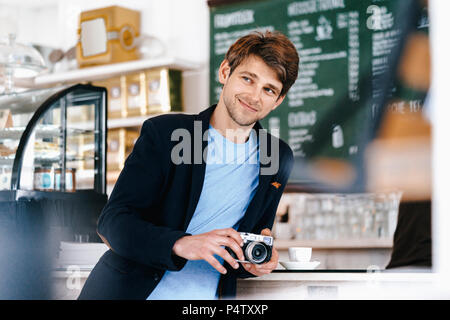 Smiling man in a cafe holding camera Stock Photo
