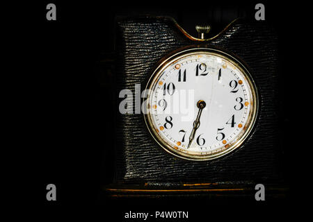 old dark-colored desk clock on a black background with space for text Stock Photo