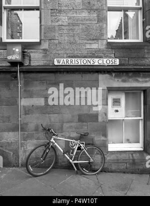 EDINBURGH, SCOTLAND - JUNE 23rd 2018: A black and white photograph of a bike leans on a wall on Warriston's Close in Edinburgh. Stock Photo