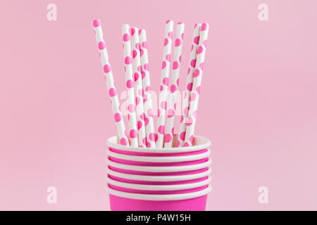 Pink paper cups with pink polka dot paper straws on pink pastel background. Set for a birthday. Stock Photo