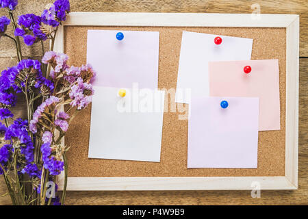Blank notes on the cork board with dry flower bouquet,wooden background. Stock Photo
