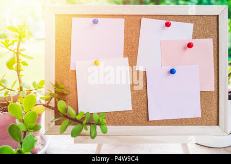 Sticky note on cork board with little tree,garden background in morning sun,empty space for text. Stock Photo