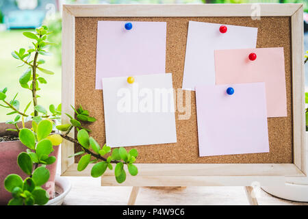 Sticky note on cork board with little tree,garden background,empty space for text. Stock Photo