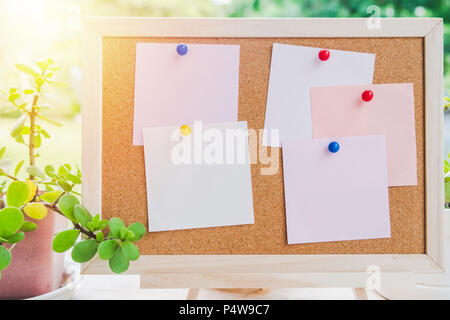 Sticky note on cork board with little tree,garden background in morning sun,empty space for text. Stock Photo