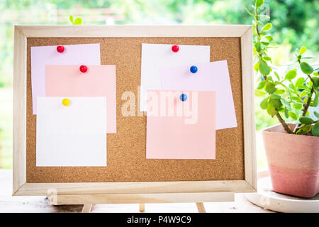 Sticky note on cork board with little tree,garden background,empty space for text. Stock Photo