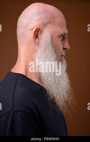 Mature bald man with long gray beard against brown background Stock Photo