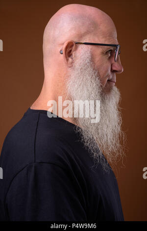 Mature bald man with long gray beard against brown background Stock Photo