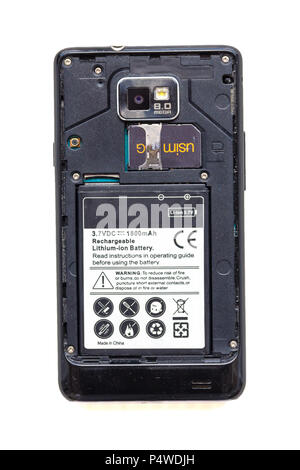 Back view of old smartphone with open cover isolated on white background. The battery and sim card are visible. Stock Photo
