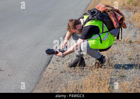 Russia, Vladivostok, 10/13/2017. Photographer makes photo with modern digital camera on event outdoor. Backpack on his back. Stock Photo