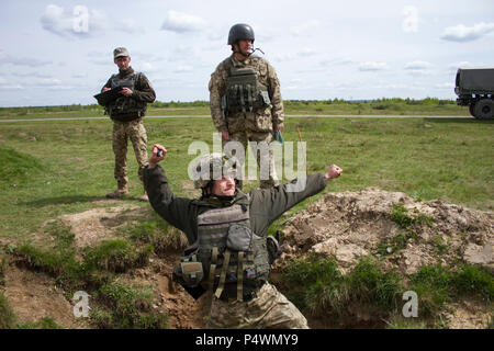 Two Yavoriv Combat Training Center trainers observe and ensure a Ukrainian soldier of the 1st Airmobile Battalion, 79th Air Assault Brigade can properly throw practice grenades before he moves on to throw live grenades during training at the Yavoriv Combat Training Center on the International Peacekeeping and Security Center, near, Yavoriv, Ukraine, on May 10.    Yavoriv CTC staff, along with mentors from the U.S. Army's 45th Infantry Brigade Combat Team, lead grenade familiarization and employment training with soldiers from the 1-79th during the battalion's rotation through the Yavoriv CTC.  Stock Photo