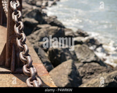 Sturdy, rusty chain blocking the sea with copy space to the right Stock Photo
