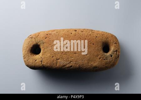 Loom weight with two holes made in earthenware 13, 5 cm x 6 cm- Chalcolithic period from the archaeological site of ' Esgaravita' in Alcalá de Henares - ' Burgo de Santiuste Museum ' (Madrid). SPAIN. Stock Photo