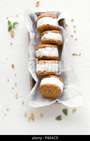 Ice cream sandwiches with nuts and wholegrain cookies. Homemade vanilla ice cream sandwiches on white background. Stock Photo