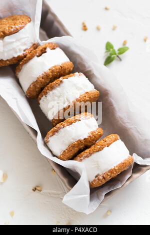 Ice cream sandwiches with nuts and wholegrain cookies. Homemade vanilla ice cream sandwiches on white background. Stock Photo