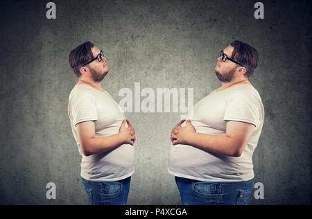 Young chubby man looking at fat himself feeling bloated. Diet and nutrition choice  healthy lifestyle concept Stock Photo