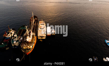 Group of Old Cargo Ships, Tugboats, Fishing Ships and Small Boats in the Coast near Rocks. Transportation. Stock Photo