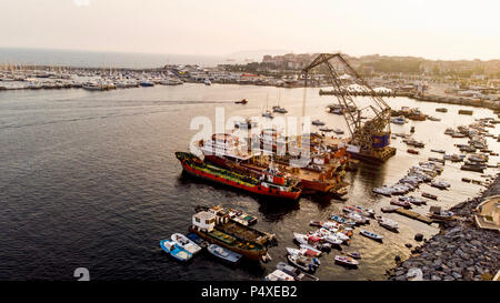 Group of Old Cargo Ships, Tugboats, Fishing Ships and Small Boats in the Coast near Rocks. Transportation. Stock Photo